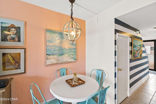 dining area with tile patterned floors, a textured ceiling, and a notable chandelier