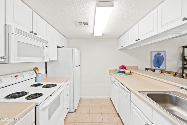 kitchen featuring sink, light tile patterned floors, a textured ceiling, white appliances, and white cabinets