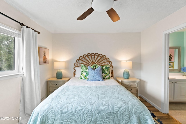 bedroom with ensuite bathroom, ceiling fan, a textured ceiling, and hardwood / wood-style flooring