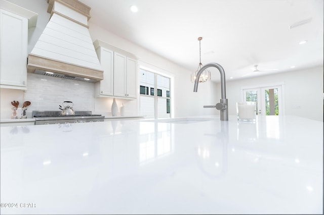 kitchen with light countertops, white cabinets, premium range hood, and hanging light fixtures