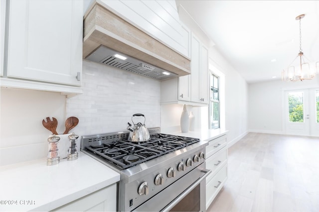 kitchen with stainless steel stove, white cabinetry, light countertops, decorative backsplash, and custom range hood