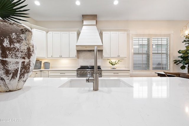 kitchen featuring white cabinets, custom range hood, high end stainless steel range, a sink, and recessed lighting