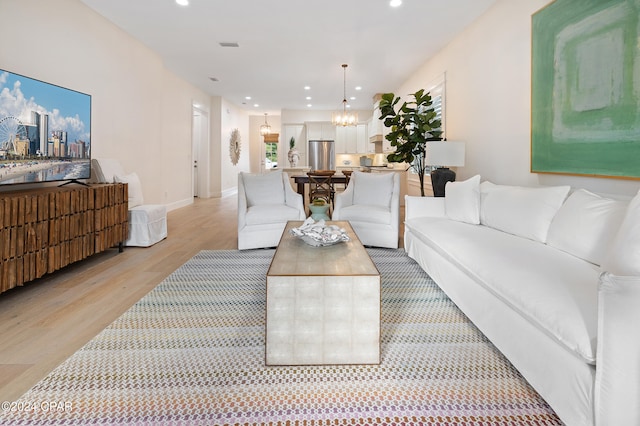 living room with light wood-style flooring, a notable chandelier, recessed lighting, visible vents, and baseboards