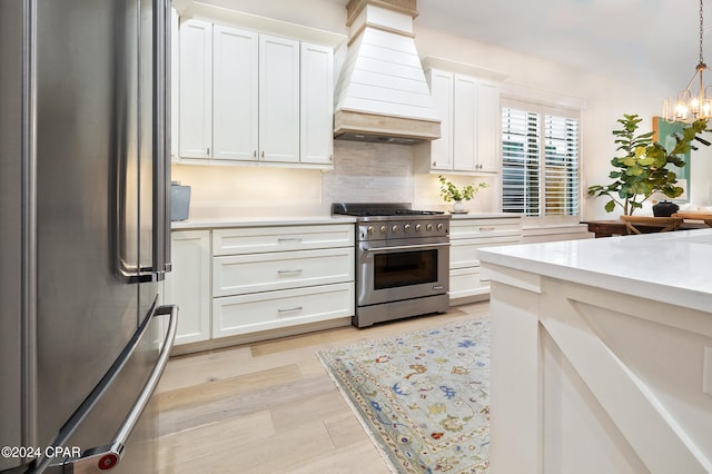 kitchen with pendant lighting, custom range hood, light hardwood / wood-style floors, white cabinetry, and stainless steel appliances