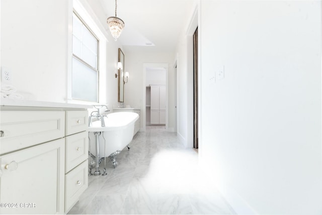 full bathroom with a chandelier, a freestanding tub, and marble finish floor