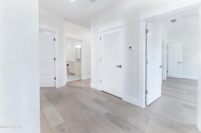 hall with light wood-type flooring, baseboards, and visible vents