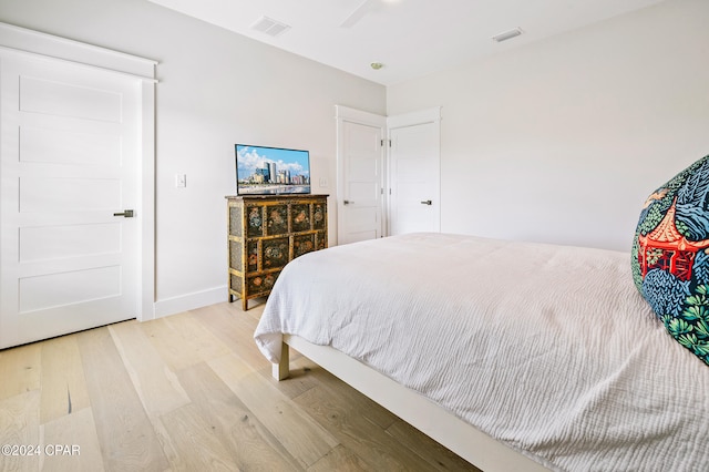 bedroom featuring baseboards, visible vents, and wood finished floors