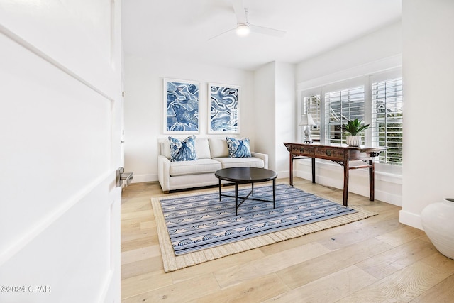 living room featuring baseboards, a ceiling fan, and wood finished floors