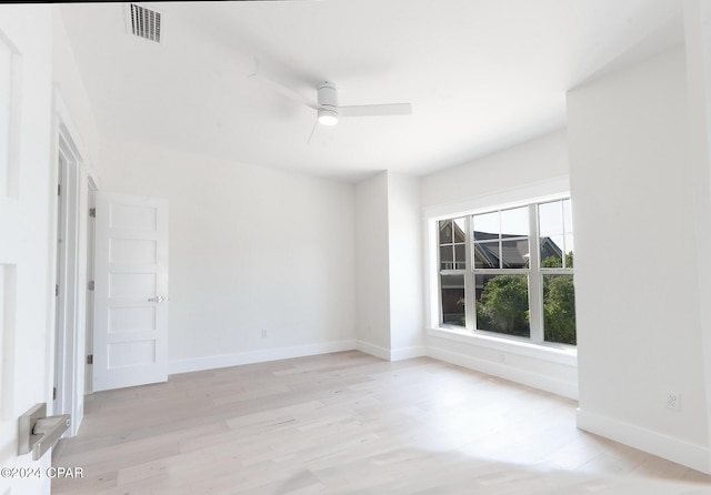 spare room featuring visible vents, ceiling fan, light wood finished floors, and baseboards