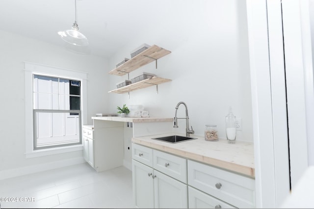 kitchen featuring white cabinets, light stone counters, decorative light fixtures, open shelves, and a sink