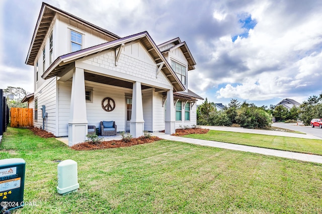 view of front facade featuring board and batten siding, a porch, a front lawn, and fence