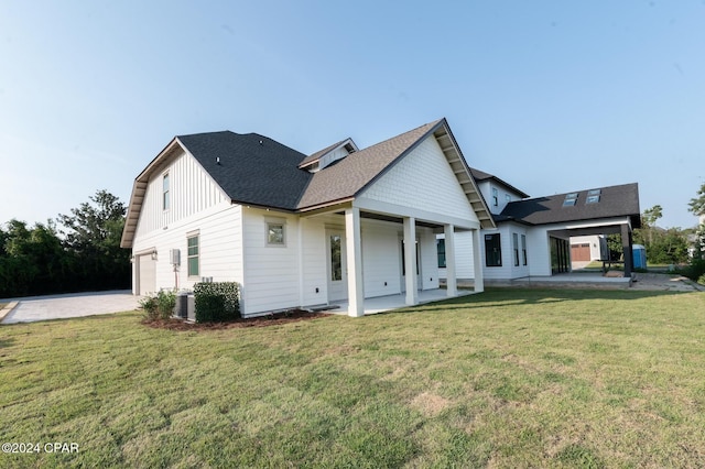 back of house featuring central AC, a garage, and a lawn