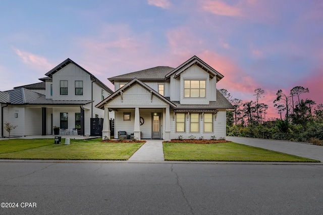 view of front of home with board and batten siding, a front yard, covered porch, and a standing seam roof