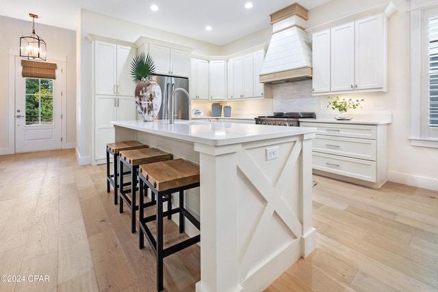 kitchen with light countertops, white cabinetry, and a center island with sink