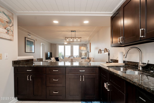 kitchen featuring sink, dark brown cabinetry, and dark stone countertops