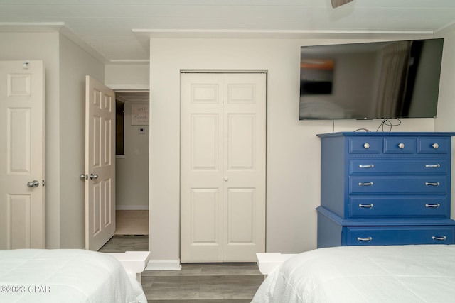 bedroom featuring a closet, wood-type flooring, and ornamental molding