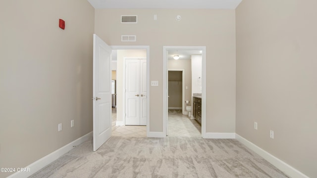 unfurnished bedroom with light carpet and ensuite bath