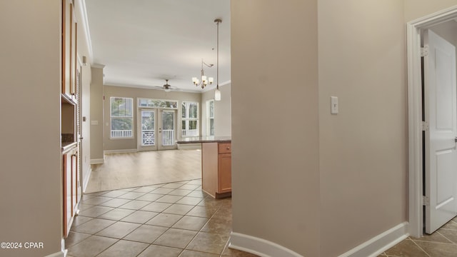 corridor featuring light tile patterned floors, crown molding, and a chandelier