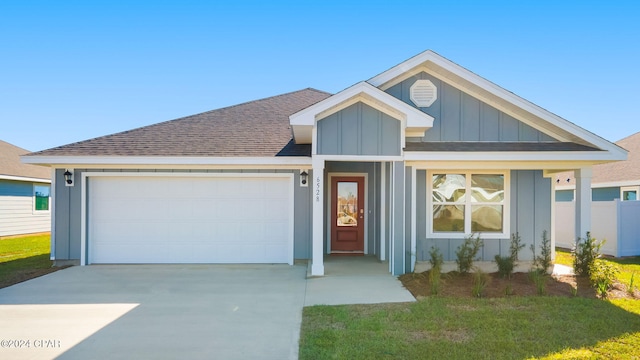 view of front of home with concrete driveway, board and batten siding, an attached garage, and roof with shingles