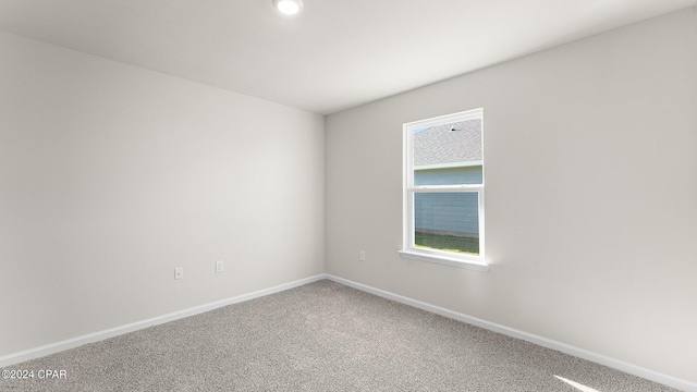 carpeted spare room featuring baseboards