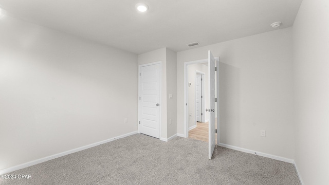 unfurnished bedroom with light carpet, visible vents, and baseboards