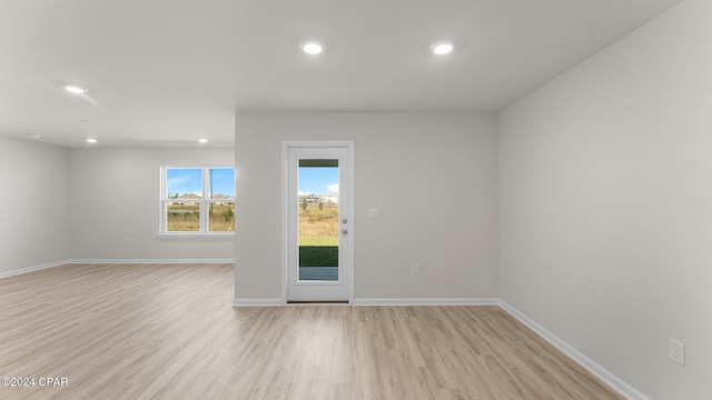 empty room with light wood finished floors, recessed lighting, and baseboards