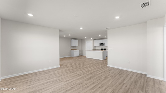 unfurnished living room featuring baseboards, light wood-style flooring, visible vents, and recessed lighting