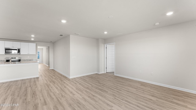 unfurnished living room with recessed lighting, baseboards, and light wood finished floors