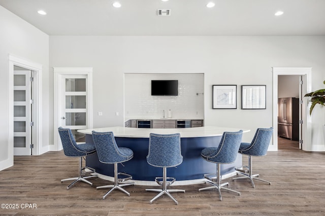 bar featuring beverage cooler, visible vents, wood finished floors, freestanding refrigerator, and recessed lighting