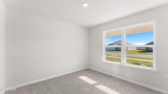 carpeted empty room featuring baseboards