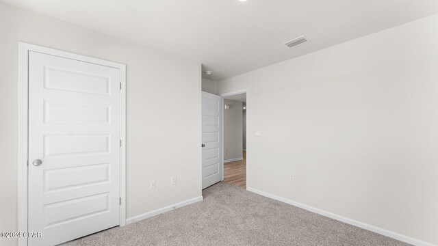 hall featuring baseboards and light colored carpet