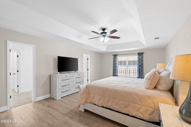 bedroom featuring a tray ceiling, light wood-type flooring, and ceiling fan