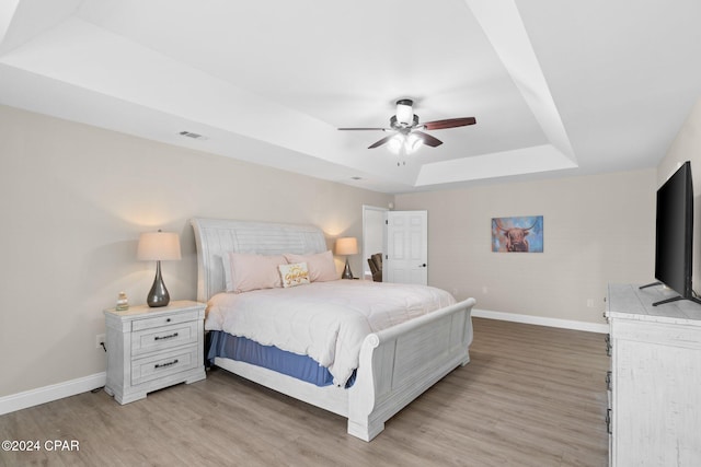 bedroom featuring hardwood / wood-style flooring, a tray ceiling, and ceiling fan