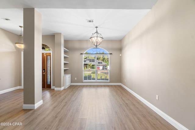 spare room with light hardwood / wood-style flooring and an inviting chandelier