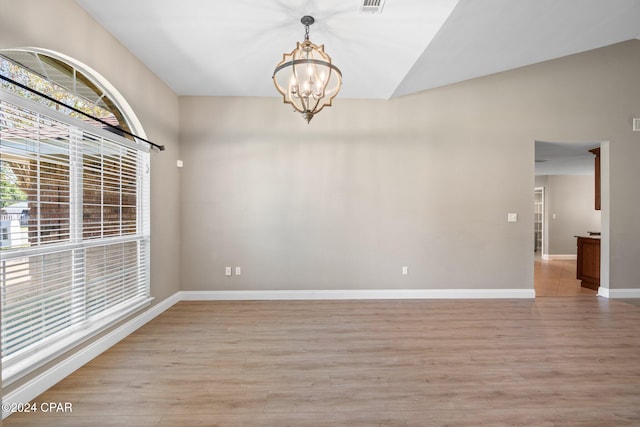 unfurnished room with lofted ceiling, a chandelier, and light wood-type flooring