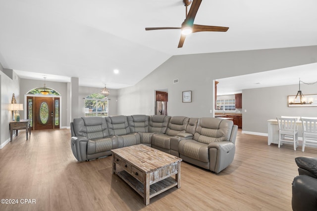 living room with lofted ceiling, ceiling fan with notable chandelier, and light wood-type flooring