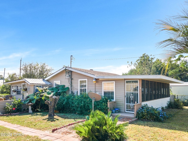 view of front of property featuring a sunroom and a front lawn