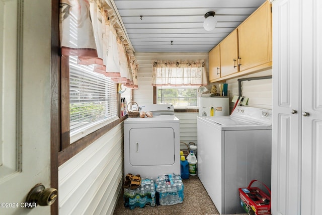 laundry room featuring cabinets, electric water heater, washing machine and clothes dryer, and wood walls