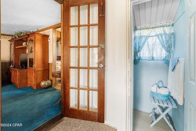 doorway with crown molding and carpet