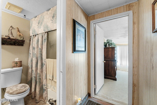 bathroom with shower / bathtub combination with curtain, toilet, and wood walls