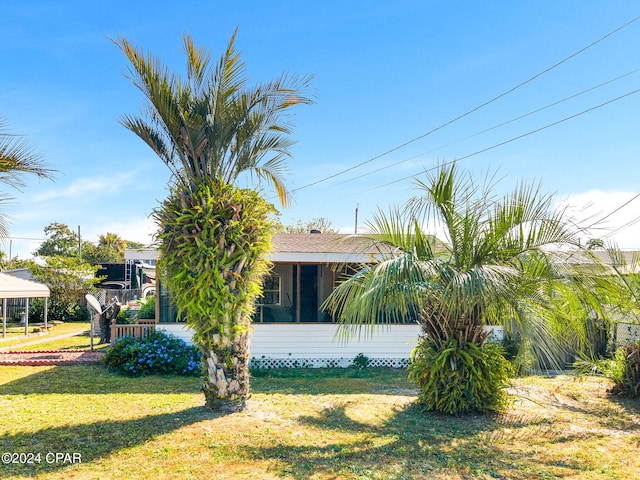 view of side of property featuring a sunroom and a lawn