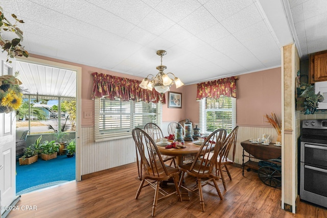 dining room with hardwood / wood-style flooring, ornamental molding, an inviting chandelier, and plenty of natural light