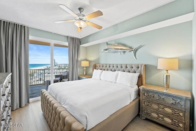 bedroom with a water view, ceiling fan, access to exterior, and light wood-type flooring