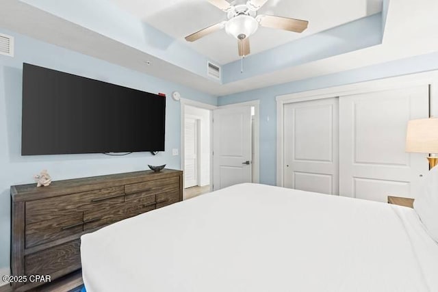 bedroom with a closet, ceiling fan, and a tray ceiling