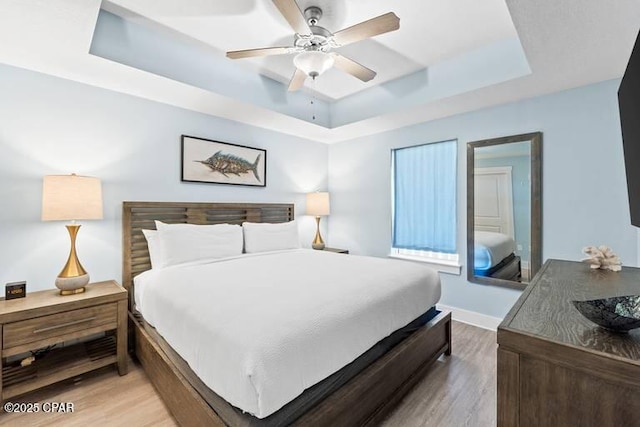 bedroom featuring a raised ceiling, hardwood / wood-style floors, and ceiling fan