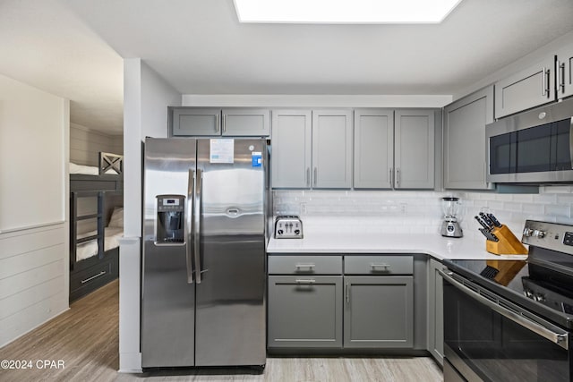 kitchen with stainless steel appliances, light wood-type flooring, and gray cabinetry