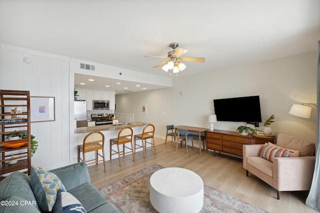 living room featuring sink, ceiling fan, and light hardwood / wood-style flooring