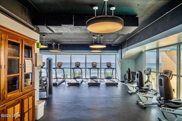 exercise room featuring a wall of windows and a water view