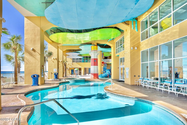 view of pool featuring a hot tub, a patio, and a water view