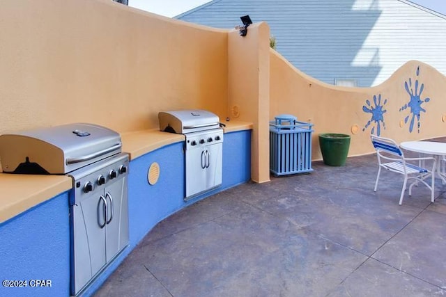 view of patio with exterior kitchen and a grill